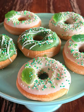 Afbeelding in Gallery-weergave laden, Groene en witte donuts met spikkels en een snoepkikker op een lichtgroen bord
